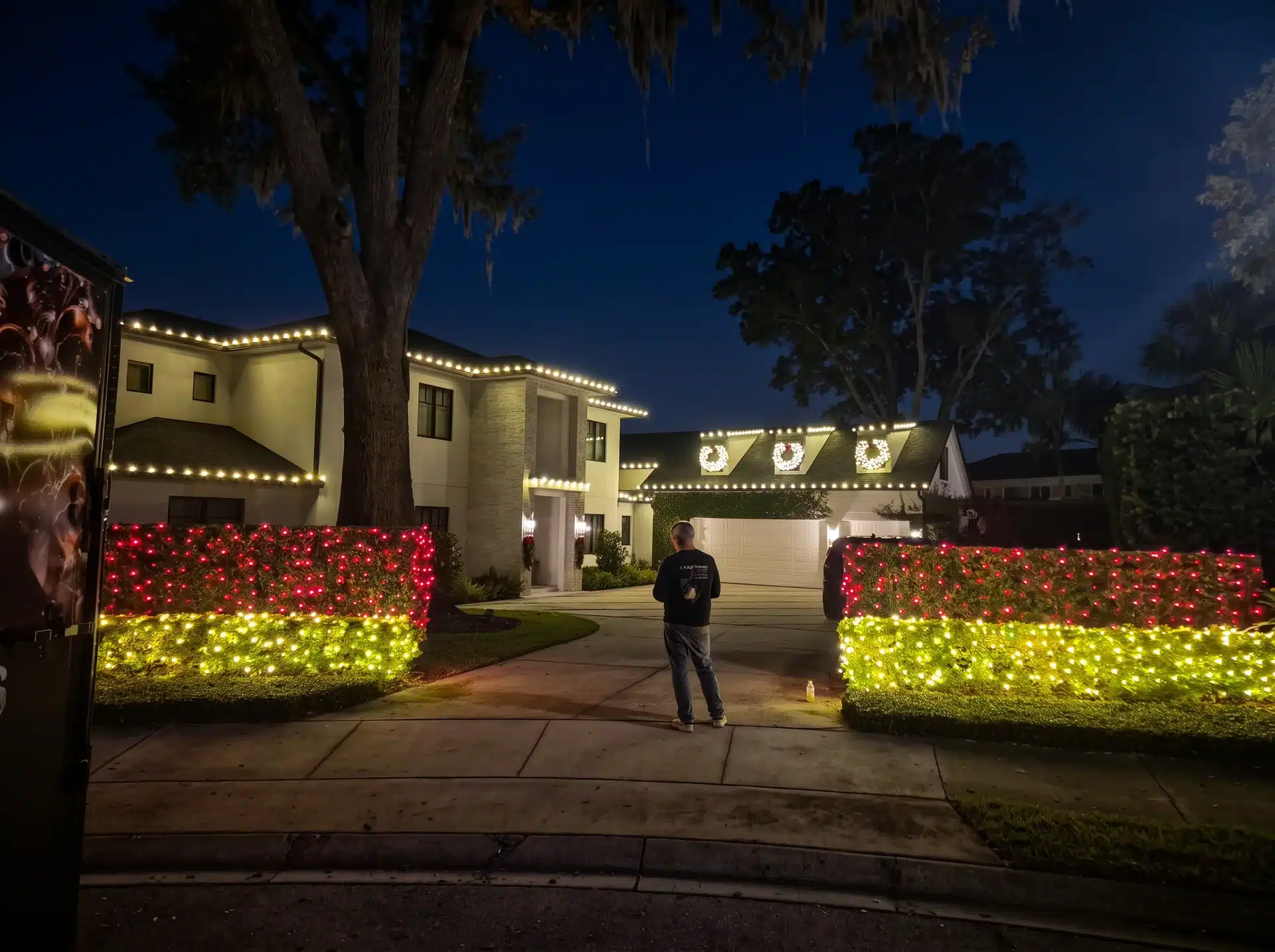 Home entrance with hedges lit in red and white Christmas lights